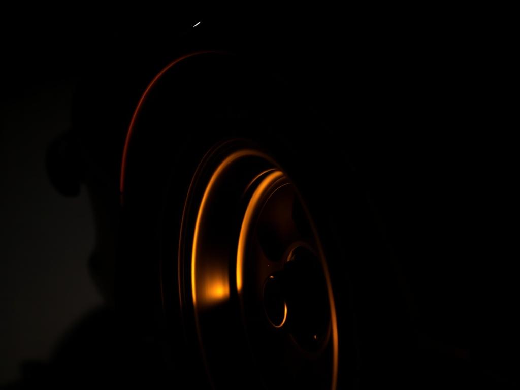 Detail of a supercar wheel and wing lit in low warm light
